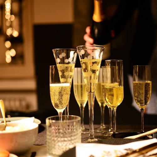 A selection of Champagne flutes containing fizz at a table in a house.